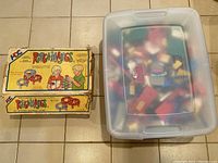 Closed box of Ringamajigs and clear plastic storage container with LEGO inside