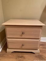 Front view of light oak night table showing two drawers with round knobs.