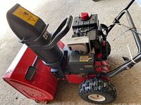 Side angle showing engine, red housing, chute and wheels