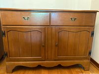 Front view of solid maple buffet cabinet showing two drawers with brass handles and two paneled doors with decorative hinges and brass knobs.