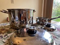 Front view of large stock pot and small saucepan with lids on table with floral tablecloth.