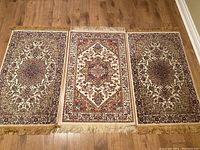 Three viscose area rugs laid side by side showing their full patterns and fringed ends