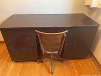 Full view of vintage solid wood desk and walnut swivel chair from behind