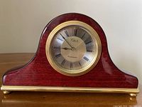 Front view of the red cherry finish Westminster chiming mantle clock by Circa showing the clock face with Roman numerals and brass-tone bezel