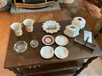 Overview of all items on wooden table including ceramics, glass, and silver plated pieces.