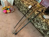 Three walking canes placed side by side on a floral patterned couch, showing handles and shaft details.