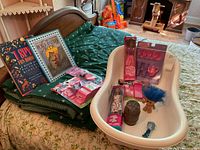 Green bassinet with several children's books and pink doll accessories on top