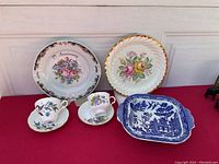 Complete set of six collectible china pieces displayed on red surface against white door.