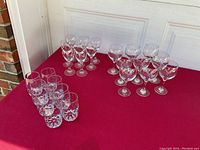 Photo showing all 26 glasses grouped by type on a red surface outside by a white door.