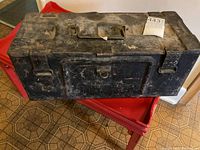 Top-side angle view of the closed heavy metal ammunition box with visible wear and label with lot number.