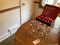 Photo of the wooden canteen box on table, and additional flatware arranged on table surface.