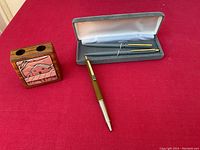 Photo showing the vintage Paper Mate pen and pencil set in original case alongside the wooden pen and pencil holder with embossed plaque on the front.
