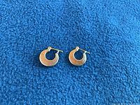 Two small baby hoop earrings, front view on blue fabric