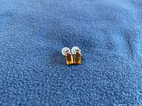 Front view of the pair of earrings showing the baguette cut citrine and diamond accent stones set in yellow gold.