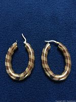 Full view of both earrings laid flat on navy background