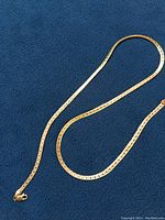 Chain laid out on blue fabric showing entire length and lobster clasp