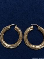 Front view of both hoop earrings laid flat on dark background