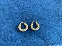 Pair of hoop earrings on blue fabric, top view