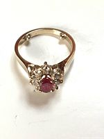 Top-down front view of ring on white background showcasing ruby and diamond halo.