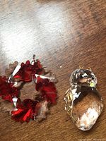 Photo of both the clear crystal owl ornament and the red crystal leaf wreath on a wood surface