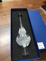 Top-down view of glass Christmas tree topper in foam-lined blue box