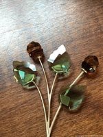 Close-up photo of the Swarovski crystal figurine showing brown hazelnut-shaped crystals and green crystal leaves on gold-tone stems.