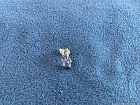 Front view of both earrings laid flat on blue fabric.