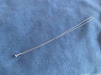 Full view of pendant and 18-inch white gold rope chain laid on blue fabric