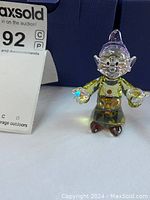 Front three-quarter view showing facial features, hat, torso and handheld crystals