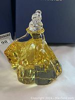 Diagonal front view of the yellow and clear crystal figurine with Swarovski box in background