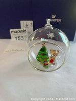 Clear glass ball Christmas ornament with snowflake design containing Swarovski crystal tree and bear figurines