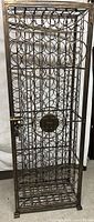 Front view of tall wrought iron wine rack with a lockable door and circular bottle holders.