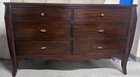 Front view of the dark wood dresser showing six drawers and curved legs.