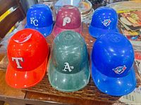 Six baseball mini helmets of various Major League Baseball teams placed on a wooden surface showing logos and colors