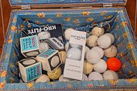 Box of mixed golf balls with branded packaging and loose balls inside a blue floral box.