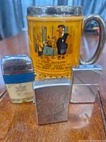 Photo showing the beer mug with humorous cartoon and all three lighters in front.