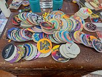A large pile of circular cardboard Pogs with colorful various printed images, featuring characters and logos.