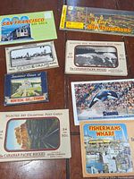 Collection of vintage travel postcards on a wooden surface featuring sets from San Francisco, Vancouver, Montreal, Canadian Rockies, Shamu, and Fisherman's Wharf