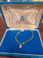 Photo of vintage gold tone Birks necklace with pear-shaped clear stone pendant in blue velvet box with white satin interior.