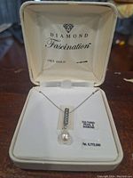 Close-up photo of the Diamond Fascination necklace in its original box showing the pendant with diamonds and cultured pearl.