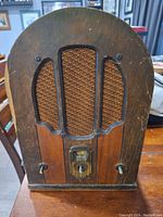 Front of the vintage radio showing rounded wooden cabinet with fabric grille and two knobs.
