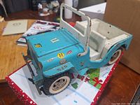 Side angled view showing blue metal body, front grille, white interior seats, and white plastic tires with rubber tread.