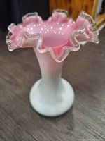 Top angle of the vase showing ruffled clear glass edges with pink fading inward and white body.