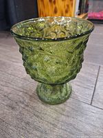Side view of vintage green glass vase showing textured, bubbled pattern and flared opening.