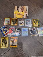 Photo showing 14 Wayne Gretzky hockey cards and one book on the floor, assorted layouts and designs.
