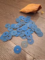 Collection of blue Canadian WW2 meat ration tokens spread on a wooden surface with a small brown cloth bag.