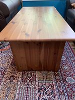 Photo of the IKEA Balby Ruta rug underneath a coffee table, showing the detailed patchwork pattern and color scheme of the rug.