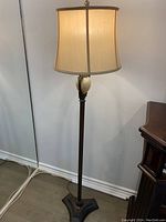Full view of the vintage floor lamp showing beige fabric shade, slender pole, and base.