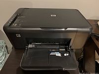Front view of the HP printer with paper tray opened.