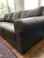 Close-up view of right armrest and cushions highlighting leather texture and stitching